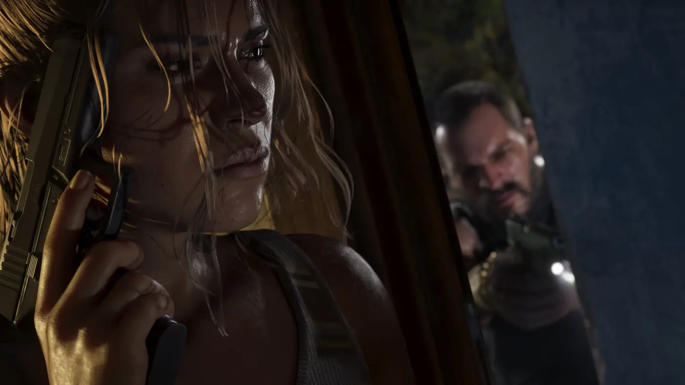 Lucia Caminos pinned against a wall, a pistol clutched close, while a man wielding a flashlight hunts her in the gloom, a scene from GTA VI