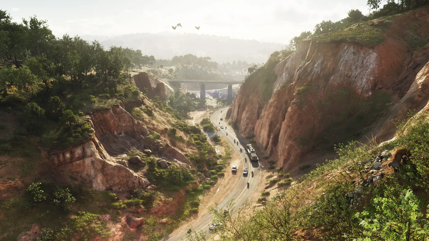 Aerial view of a red-rock canyon in Mount Kalaga in GTA VI, a winding road along the valley floor traveled by motorcycles and cars, a bridge spanning the gorge, wooded hills on the horizon